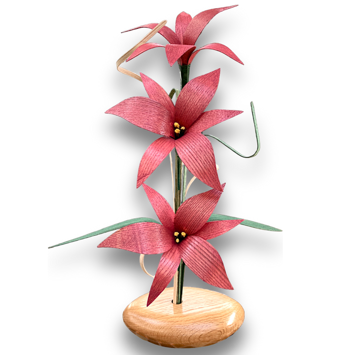 Mauve Lily Wood Flower Arrangement. Handcrafted in the Northern USA, this arrangement features stunning lilies in a rich red oak vase, complemented by delicate grasses and leaves.