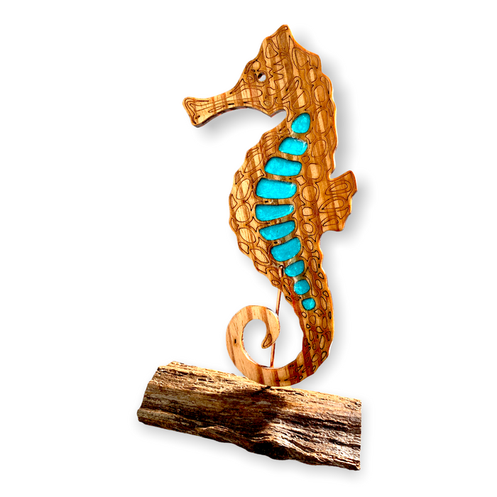 This single wooden seahorse with aqua blue epoxy accents is displayed on a rustic pine wood base and basks in the sunlight..