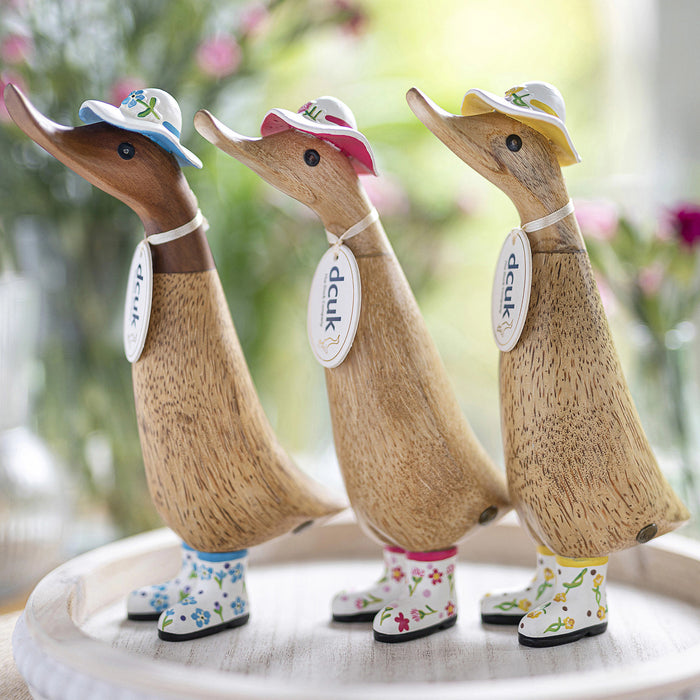 Handmade DCUK wood duckling wearing a carnation flower hat and matching boots, part of the DCUK wooden gifts collection.