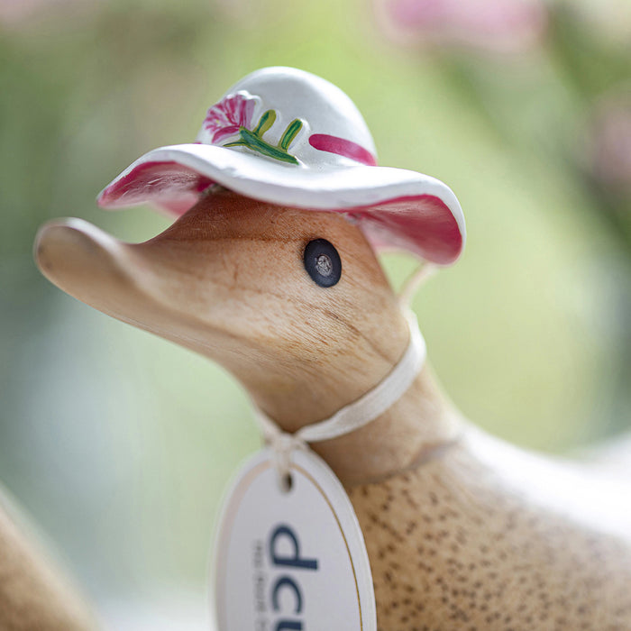 Handcrafted DCUK wood duck with a carnation flower hat and matching boots, showcasing charming handmade wooden gift craftsmanship.