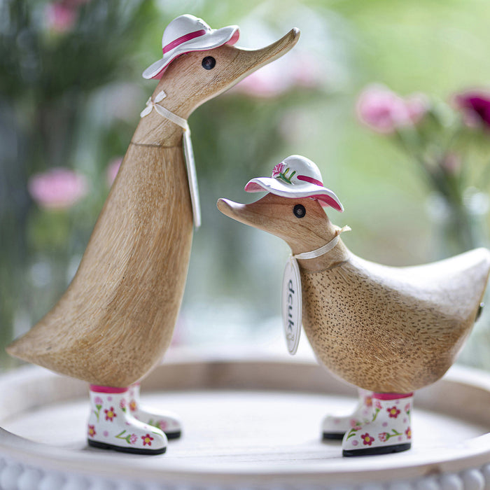 Handmade DCUK wood duck wearing a carnation flower hat and matching boots, showcasing detailed craftsmanship and charming design.