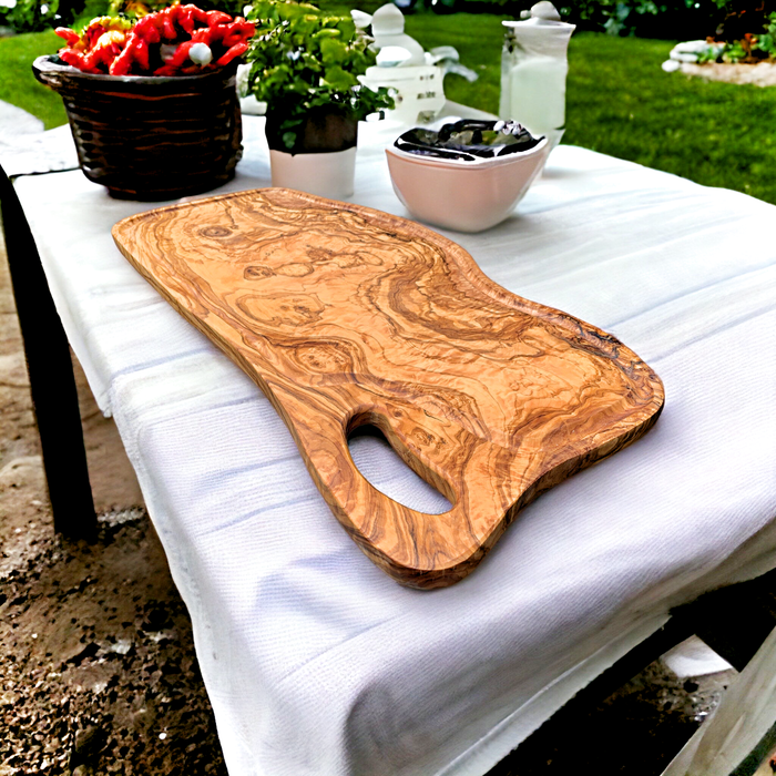 Oblong Olive Wood Cutting Board: Rustic elegance with beautiful wood grain, fluid lines, and a grip handle. Perfect for presentations and charcuterie. Size: 23-1/2 x 11 x 1/2 inches.