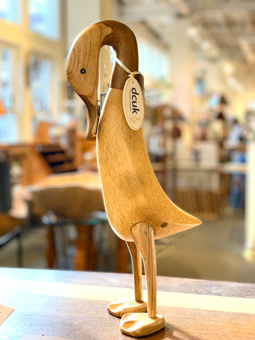 Handcrafted bamboo root life-size wooden duck statue in a whimsical pose displayed on a table in a bright, cozy room