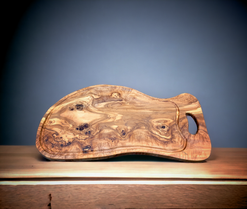 This one-of-a-kind  board showcases a fluid organic shape, accentuated by the captivating wood grain of olive wood.
