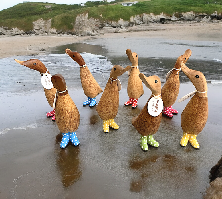 Handcrafted bamboo and teak wood ducklings with spotty boots on a beach, perfect for home decor or gifting