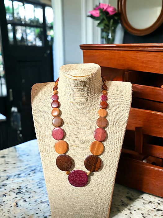 Long Emily Wood Disc Necklace in Central American Woods displayed on a mannequin in a cozy room ambiance