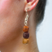 Close-up of small three bead exotic woods earrings in drop style on a person, highlighting natural hues and textures.