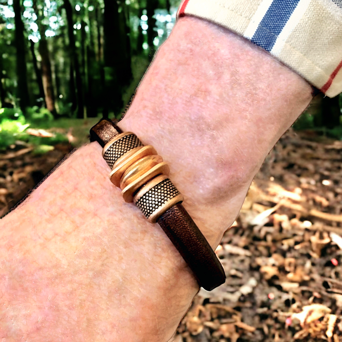 Man wearing a Track Leather Bracelet with copper finish in an outdoor setting, showcasing stylish and durable design for men and women.
