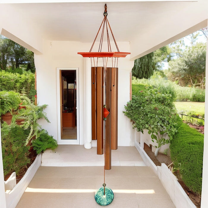 Woodstock Turquoise Wind Chime with bronze aluminum tubes and cherry finished ash wood, hanging in a garden setting