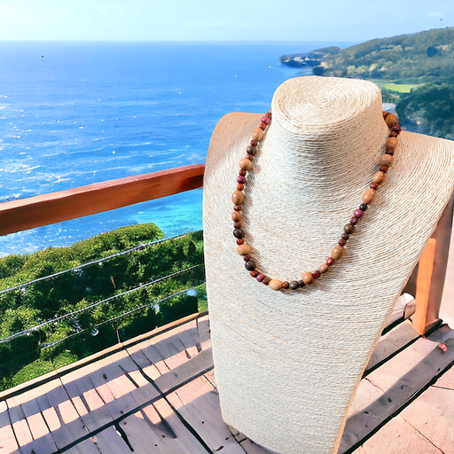 Beaded holiday wood necklace displayed on a mannequin with ocean view background, featuring natural wood colors and exotic materials.