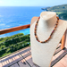 Beaded holiday wood necklace displayed on a mannequin with ocean view background, featuring natural wood colors and exotic materials.