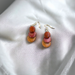 Stylish small wood earrings with overlapping discs in purple heart, cocobola, and pau amarillo, displayed on white fabric