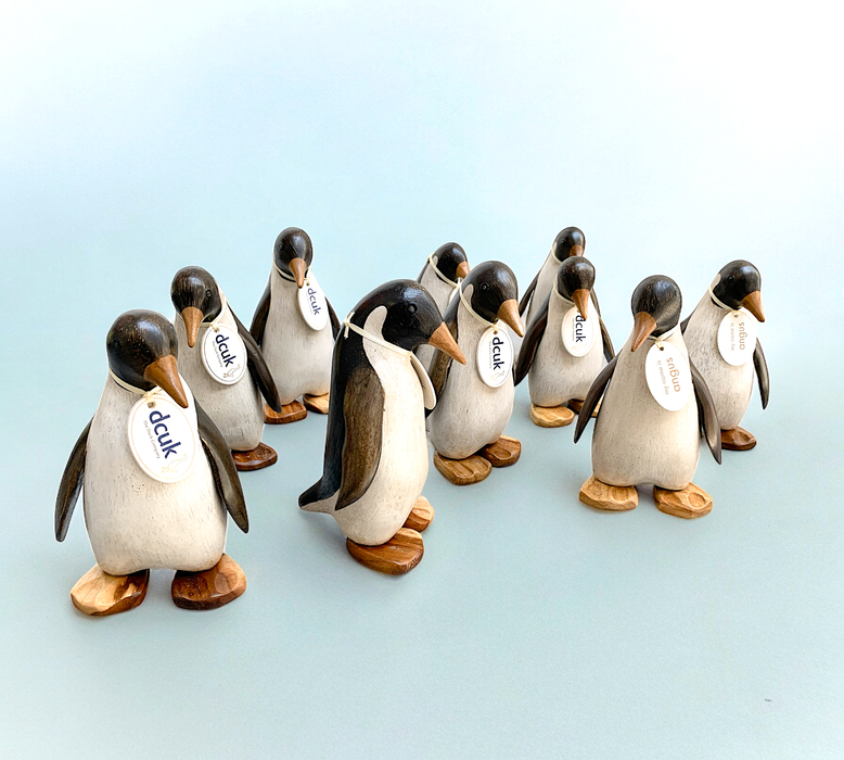 Handcrafted wooden Emperor Penguin figurines with name tags displayed on light background
