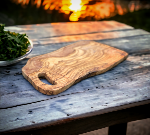 Extra large olive wood cutting board great for entertaining. Exceptionally beautiful wood  grain.  Looks more like burl wood. Shown outdoors on a rustic table  with sunset in background.