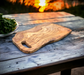 Extra large olive wood cutting board great for entertaining. Exceptionally beautiful wood  grain.  Looks more like burl wood. Shown outdoors on a rustic table  with sunset in background.