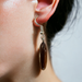 Close-up of a person wearing handmade 2-Inch Oval Wood Drop Earring in rich wood tone with a silver hook.