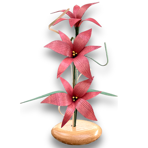 Mauve Lily Wood Flower Arrangement. Handcrafted in the Northern USA, this arrangement features stunning lilies in a rich red oak vase, complemented by delicate grasses and leaves. 