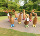 Handcrafted bamboo and teak wood ducklings with colorful spotty boots and name tags on a garden path.