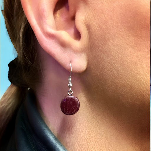Woman wearing Catrina wood drop earring with flat round bead in burgundy purple heart wood.